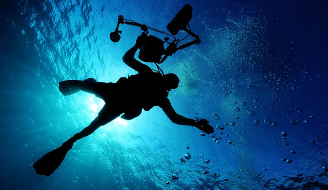 Looking up at a silhouette of a diver with camera underwater
