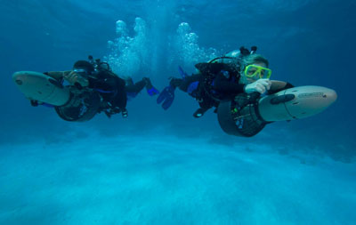 Two divers using propulsion vehicles